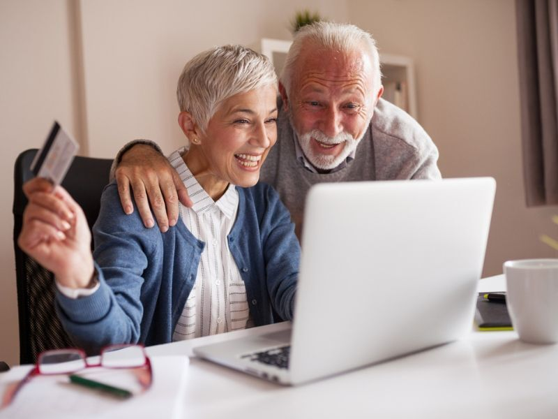 An older couple smile at a laptop