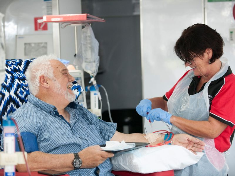 A man on dialysis laughs with a health professional