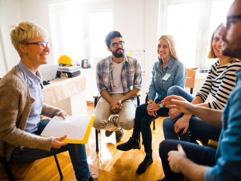 Five people sitting down and talking