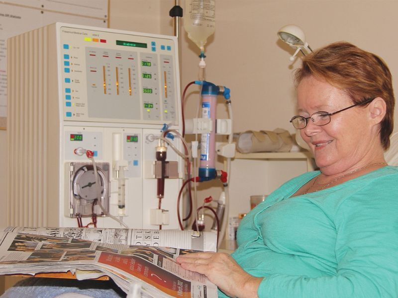 A woman on dialysis reading a newspaper